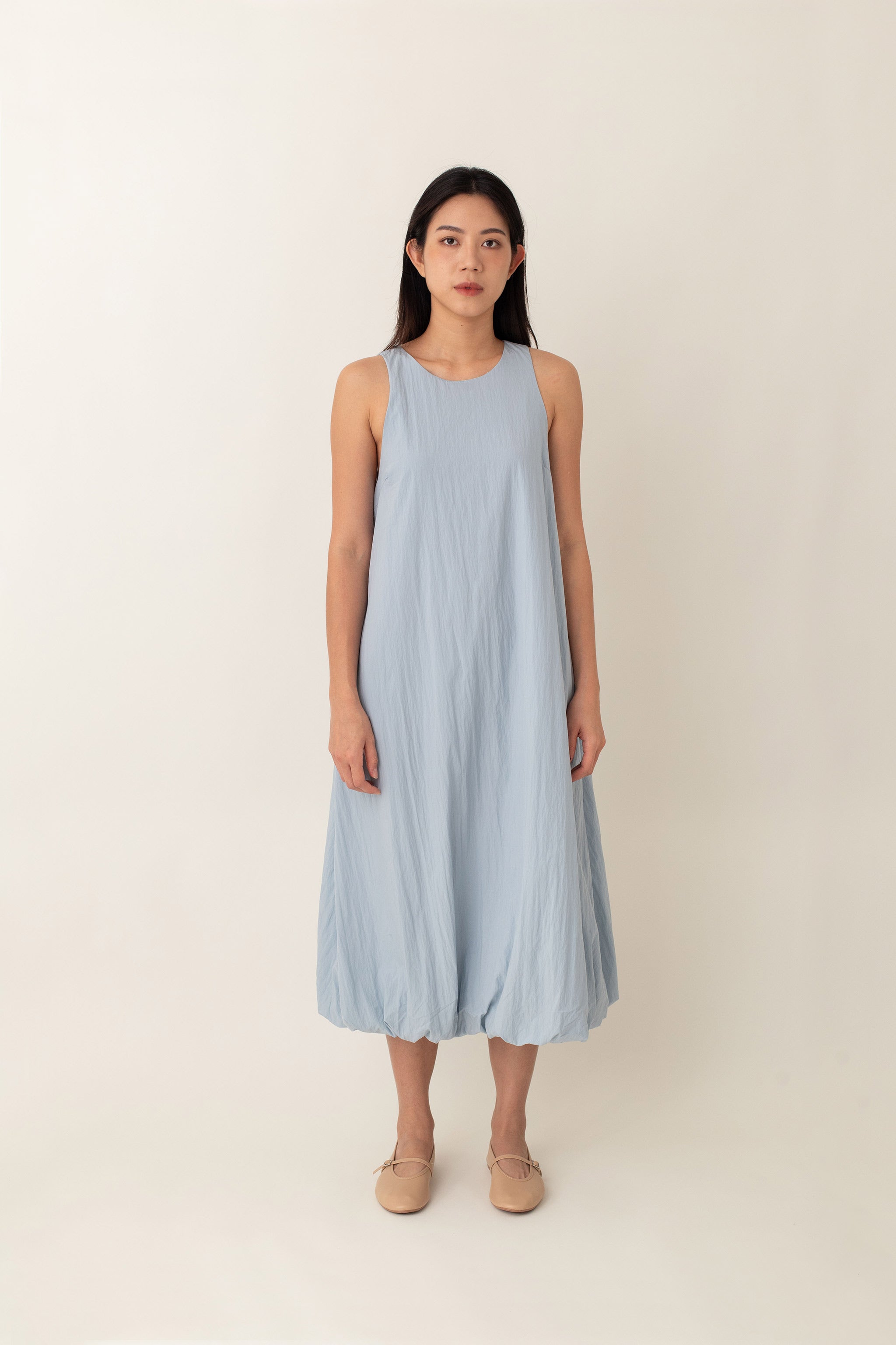 With its airy balloon silhouette that tapers gently at the hem, the Saffron Dress offers a playful and relaxed vibe. The dress has a simple sleeveless design with a round neckline and handy side pockets, perfect for stashing your essentials. The back zipper makes it easy to slip on and off, adding to its effortless appeal.